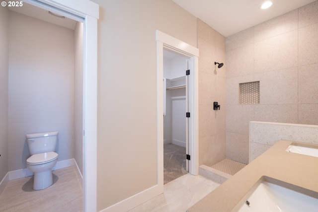 bathroom featuring sink, toilet, and tiled shower