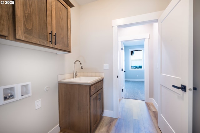 washroom with cabinets, washer hookup, sink, and light wood-type flooring