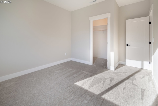 unfurnished bedroom featuring a spacious closet, light carpet, and a closet