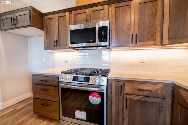 kitchen featuring appliances with stainless steel finishes, decorative backsplash, and light hardwood / wood-style flooring