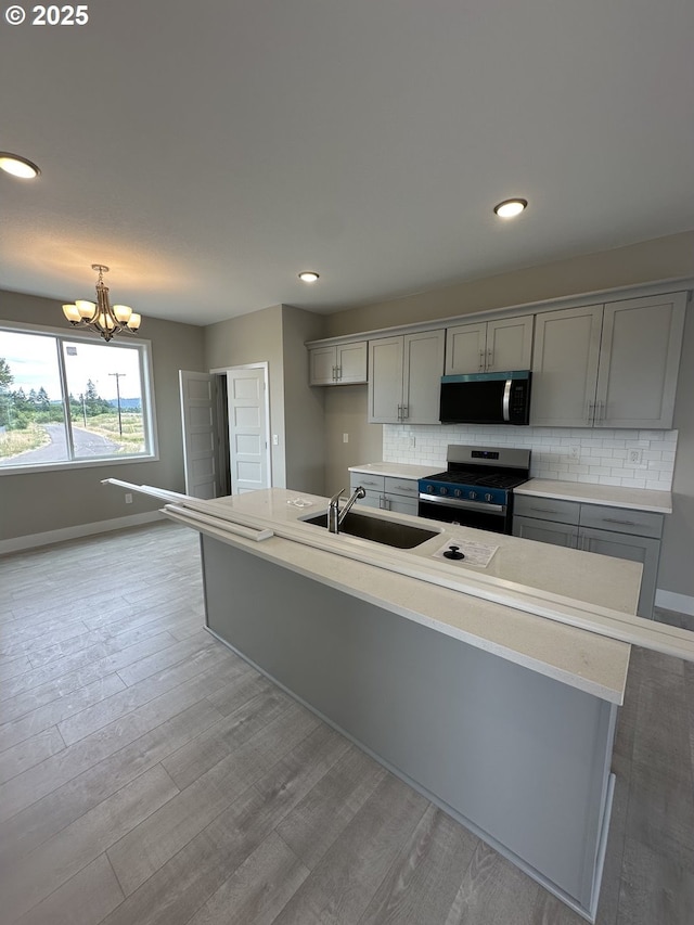 1775 S Murphy Dr, Newberg, OR 97132 - kitchen featuring appliances with stainless steel finishes, gray cabinetry, backsplash, a chandelier, and light wood finished floors