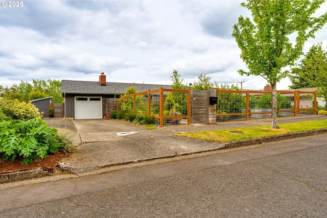 view of front of home featuring driveway, a chimney, a gate, and a garage