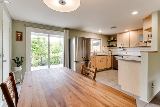kitchen with appliances with stainless steel finishes, open shelves, light brown cabinetry, light tile patterned flooring, and tasteful backsplash