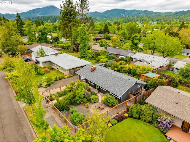 aerial view of residential area featuring a mountainous background and a forest