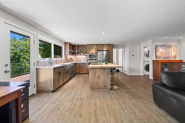 37333 NE Reed Rd, Corbett, OR 97019 - kitchen featuring appliances with stainless steel finishes, stacked washer / drying machine, open floor plan, light wood finished floors, and recessed lighting