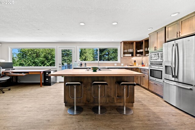 37333 NE Reed Rd, Corbett, OR 97019 - kitchen featuring appliances with stainless steel finishes, healthy amount of natural light, a kitchen island, light wood finished floors, and a textured ceiling