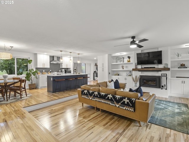 living room featuring ceiling fan, a healthy amount of sunlight, and light wood-type flooring