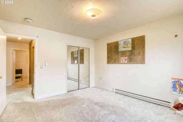 unfurnished bedroom with a baseboard heating unit, baseboards, a textured ceiling, and a closet