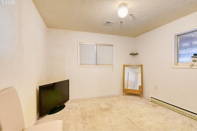 interior space with baseboards, baseboard heating, a textured ceiling, and visible vents