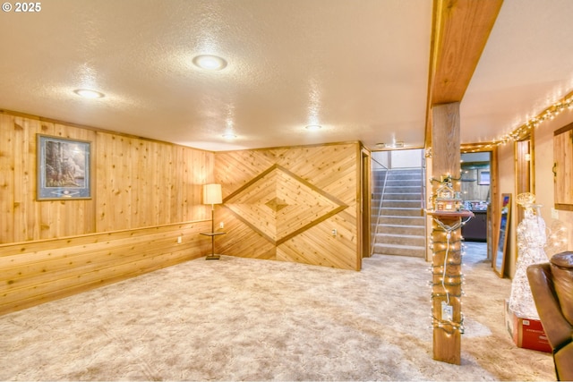 finished basement with carpet floors, wood walls, and stairs