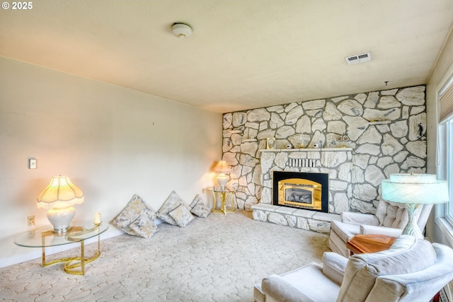 living room with a stone fireplace and visible vents