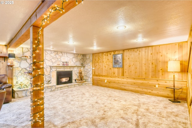 unfurnished living room featuring carpet flooring, a fireplace, wood walls, and a textured ceiling