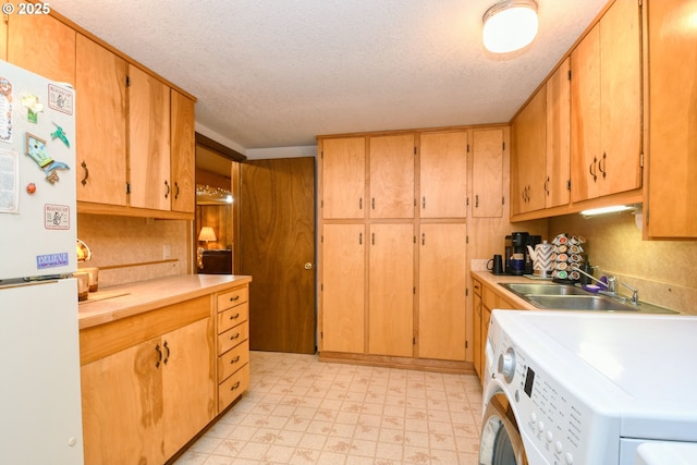 kitchen with a sink, a textured ceiling, freestanding refrigerator, light countertops, and light floors