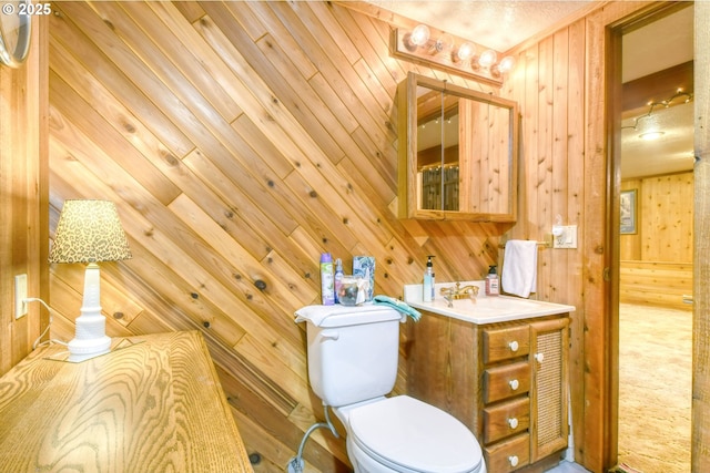 bathroom featuring vanity, toilet, and wood walls