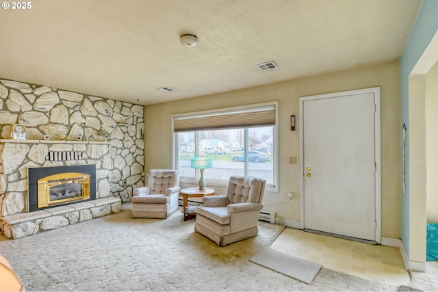 sitting room featuring a stone fireplace, visible vents, a baseboard heating unit, and a textured ceiling