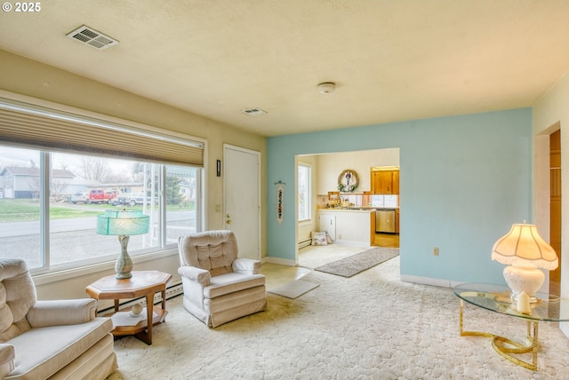 sitting room with visible vents, baseboards, light colored carpet, and baseboard heating