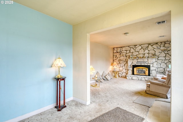 living room with a stone fireplace, baseboards, and visible vents