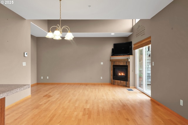 425 SE Shell Ave Unit 4, Depoe Bay, OR 97341 - unfurnished living room featuring wood finished floors, a chandelier, a tile fireplace, and baseboards