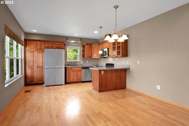425 SE Shell Ave Unit 4, Depoe Bay, OR 97341 - kitchen featuring stainless steel appliances, a peninsula, light wood-style floors, glass insert cabinets, and brown cabinets
