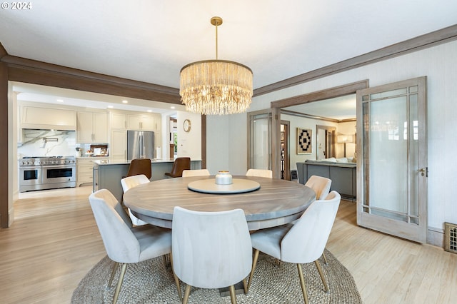 dining area with a chandelier, ornamental molding, and light wood-style flooring