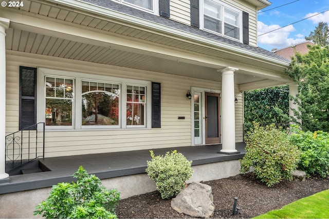 entrance to property with a shingled roof and a porch