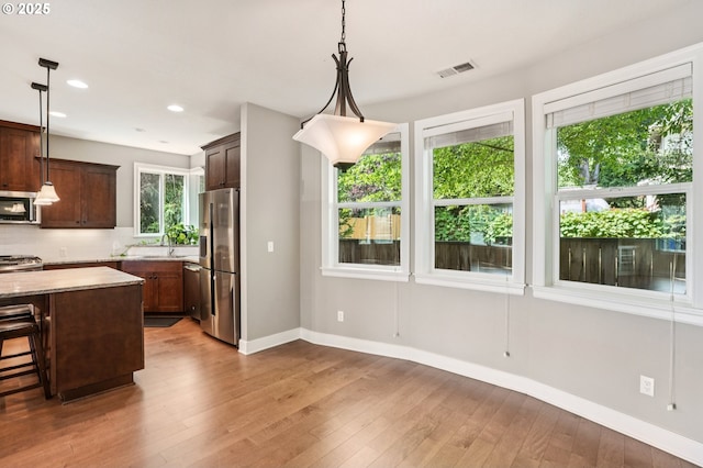 665 NE Skidmore St, Portland, OR 97211 - kitchen with appliances with stainless steel finishes, tasteful backsplash, hardwood / wood-style floors, recessed lighting, and dark brown cabinets