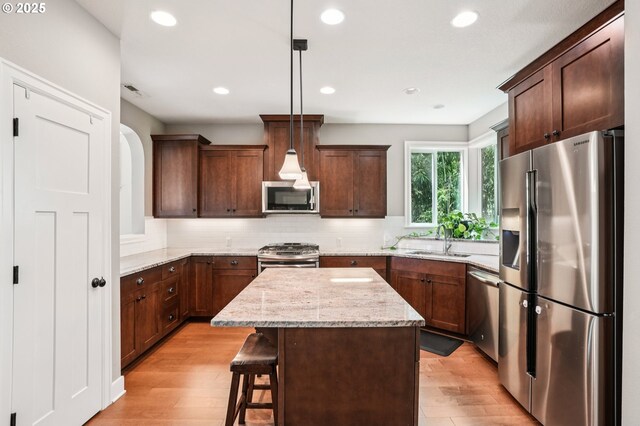 665 NE Skidmore St, Portland, OR 97211 - kitchen featuring appliances with stainless steel finishes, light wood-style flooring, backsplash, recessed lighting, and light stone countertops