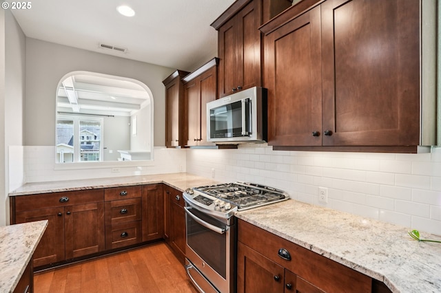 665 NE Skidmore St, Portland, OR 97211 - kitchen with stainless steel appliances, light wood finished floors, backsplash, light stone countertops, and recessed lighting