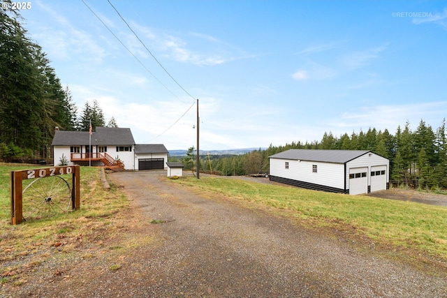 view of front of house featuring an outbuilding, a detached garage, and a front yard