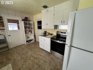 215 Hill Ave, Milton-Freewater, OR 97862 - kitchen with freestanding refrigerator, electric stove, and white cabinetry