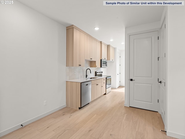 1612 SE Morrison St Unit 2, Portland, OR 97214 - kitchen featuring stainless steel appliances, a sink, light brown cabinetry, tasteful backsplash, and light countertops