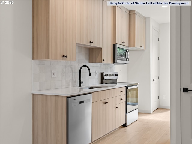 1612 SE Morrison St Unit 2, Portland, OR 97214 - kitchen featuring appliances with stainless steel finishes, light brown cabinets, light countertops, light wood-style floors, and backsplash