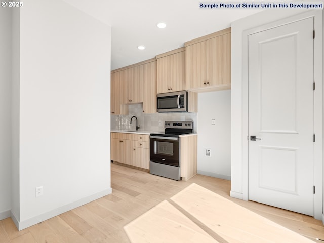 1612 SE Morrison St Unit 2, Portland, OR 97214 - kitchen with stainless steel appliances, a sink, light brown cabinetry, light countertops, and tasteful backsplash
