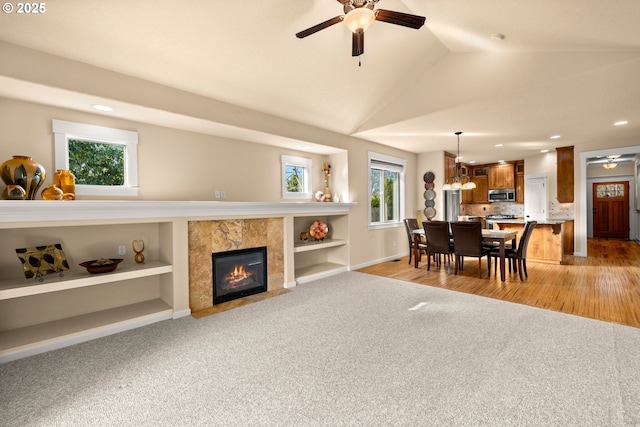 living area featuring ceiling fan, vaulted ceiling, a healthy amount of sunlight, and light carpet