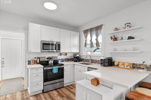 kitchen featuring white cabinetry, appliances with stainless steel finishes, sink, and a breakfast bar area