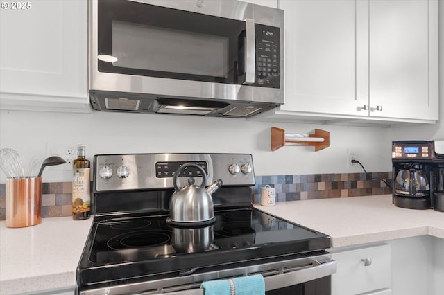 kitchen featuring appliances with stainless steel finishes, white cabinets, and light stone counters