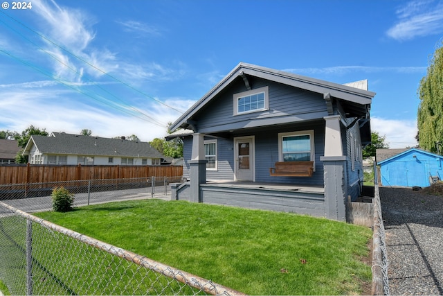 view of front of home featuring a front yard, covered porch, and a storage unit