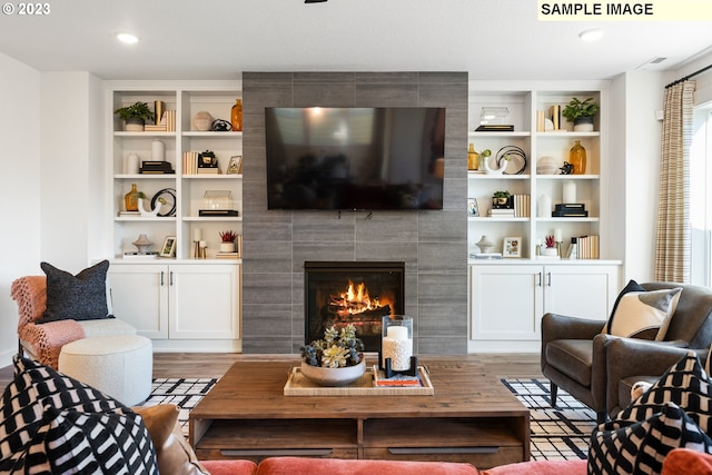 living room with hardwood / wood-style flooring, a fireplace, and built in shelves