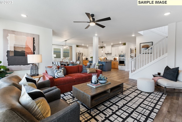 living area featuring light wood-style flooring, stairway, a ceiling fan, and recessed lighting