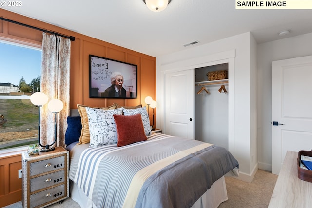 bedroom with a closet, light colored carpet, and visible vents