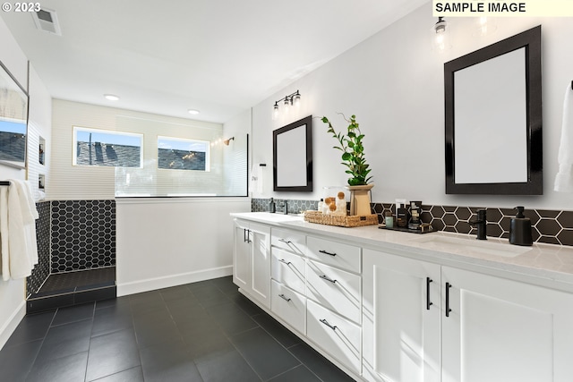 bathroom with a tile shower, backsplash, vanity, and tile patterned floors