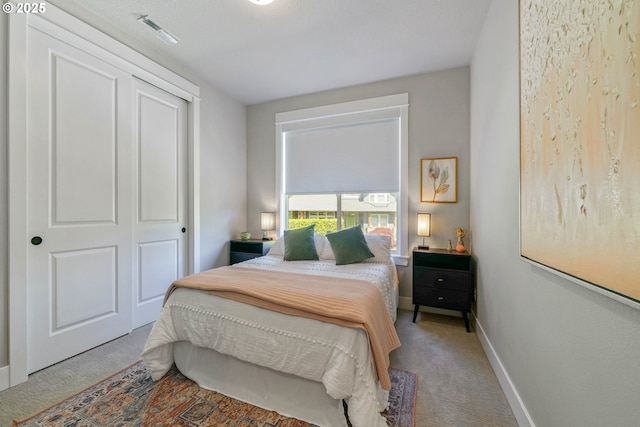 carpeted bedroom featuring a closet, visible vents, and baseboards