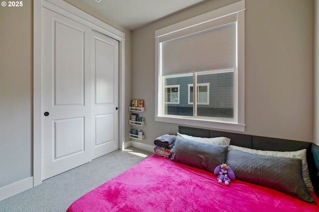 carpeted bedroom featuring baseboards and a closet