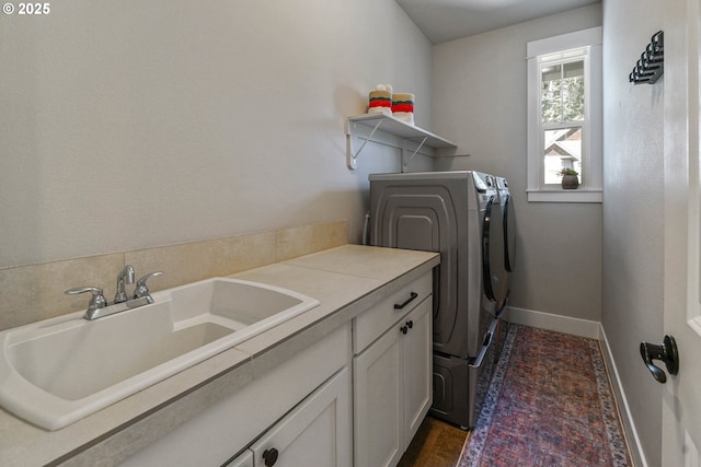 laundry area featuring cabinet space, separate washer and dryer, baseboards, and a sink
