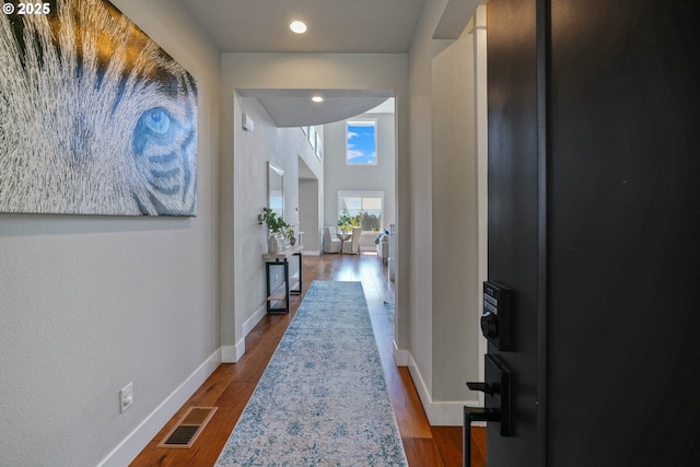 hallway featuring baseboards, visible vents, dark wood-type flooring, and recessed lighting
