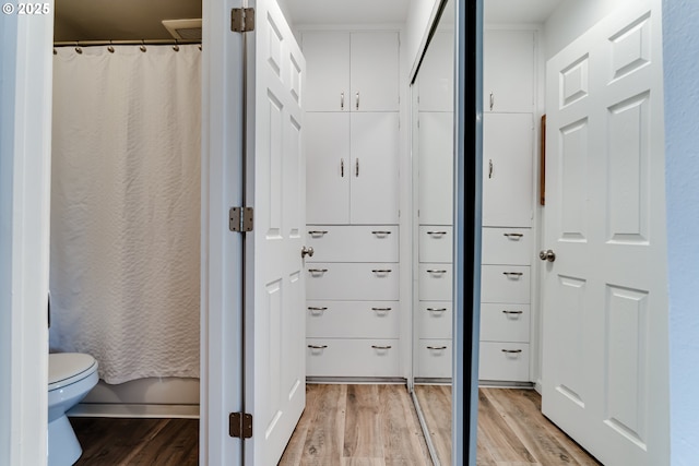 full bath featuring curtained shower, toilet, and wood finished floors