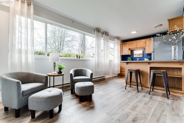 living area featuring light wood-style floors, a baseboard heating unit, and baseboard heating