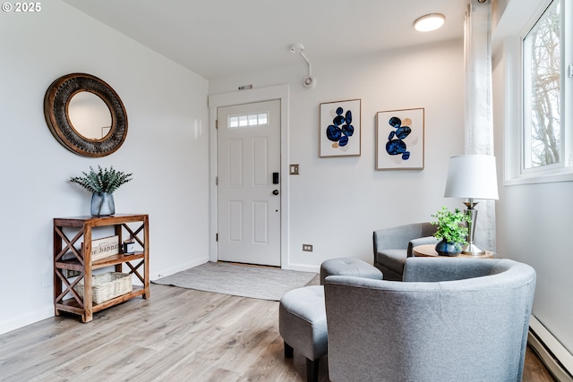 entryway featuring light wood-type flooring, baseboards, baseboard heating, and a healthy amount of sunlight