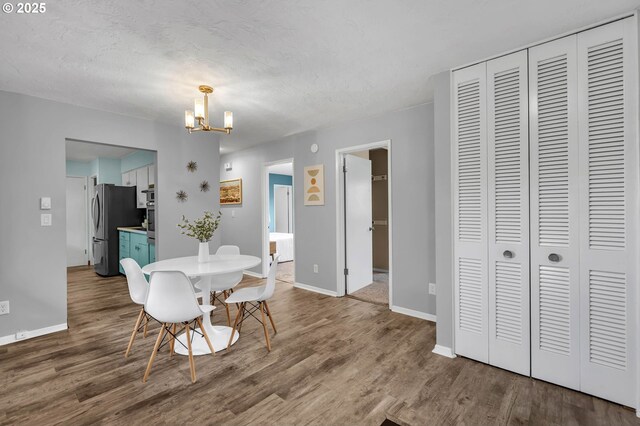 dining room with an inviting chandelier, a textured ceiling, baseboards, and wood finished floors