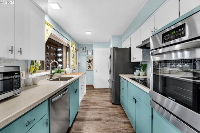 kitchen with a sink, white cabinets, light countertops, appliances with stainless steel finishes, and backsplash